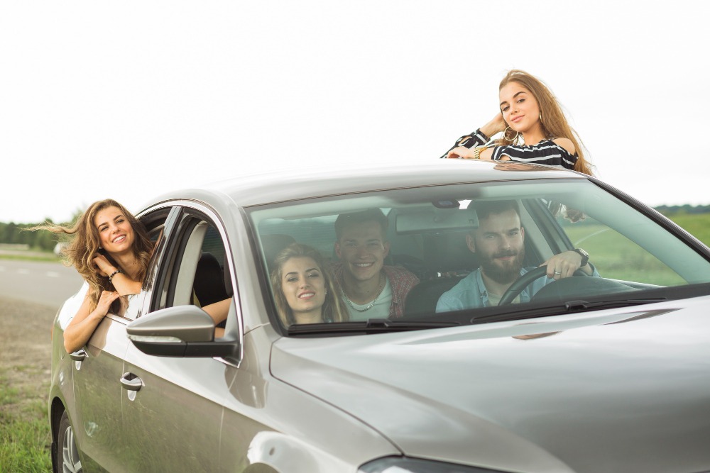 5 young adults in a silver car